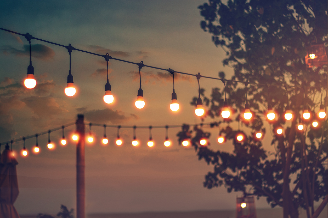 blurred bokeh light on sunset with yellow string lights decor in beach restaurant Deck building Paso Robles, CA