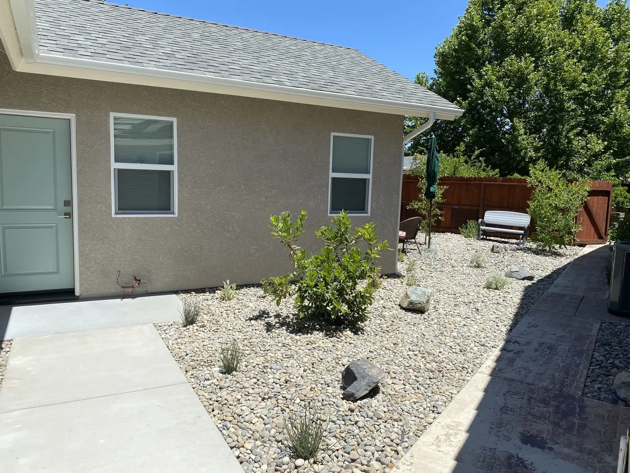 Gravel xeriscape beds with boulders along a concrete path