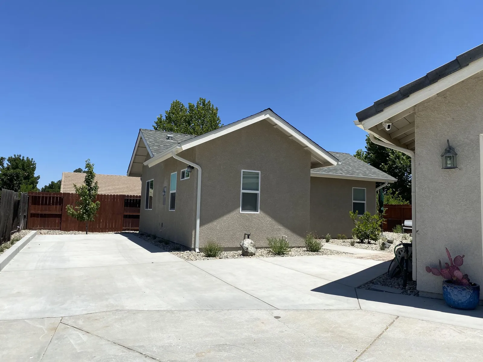 Wide concrete parking pad beside a stucco cottage with gravel planting strips