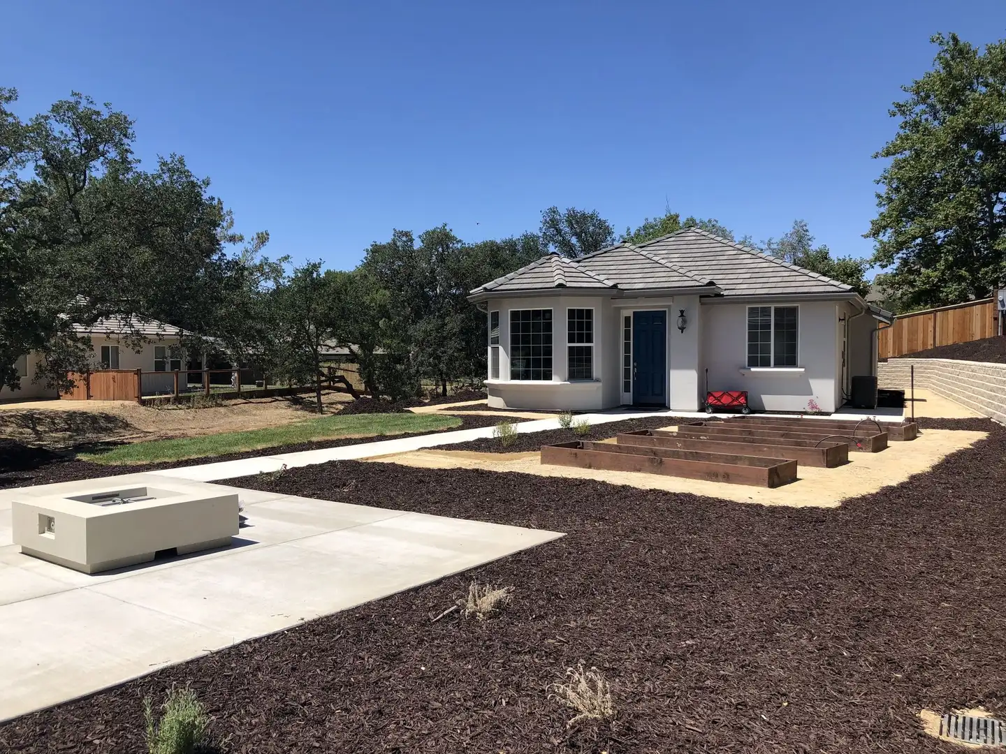 Concrete patio with a fire bowl and raised garden beds