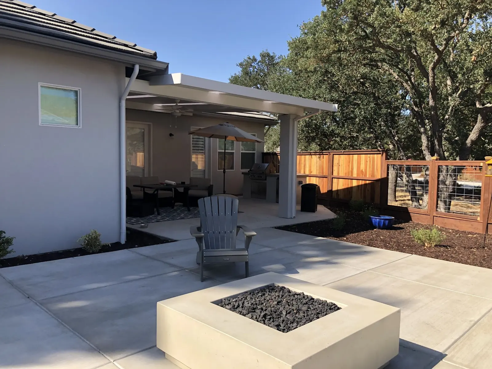 Concrete patio with a fire table under an aluminum patio cover