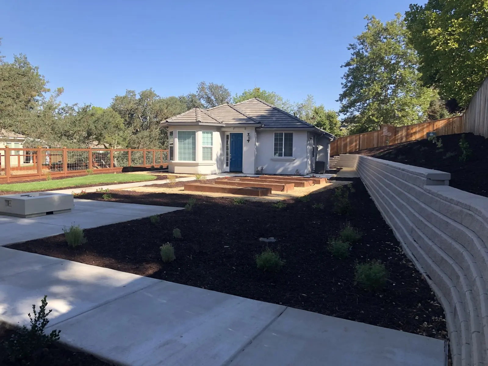 Concrete walkway beside mulched planting beds and a block wall