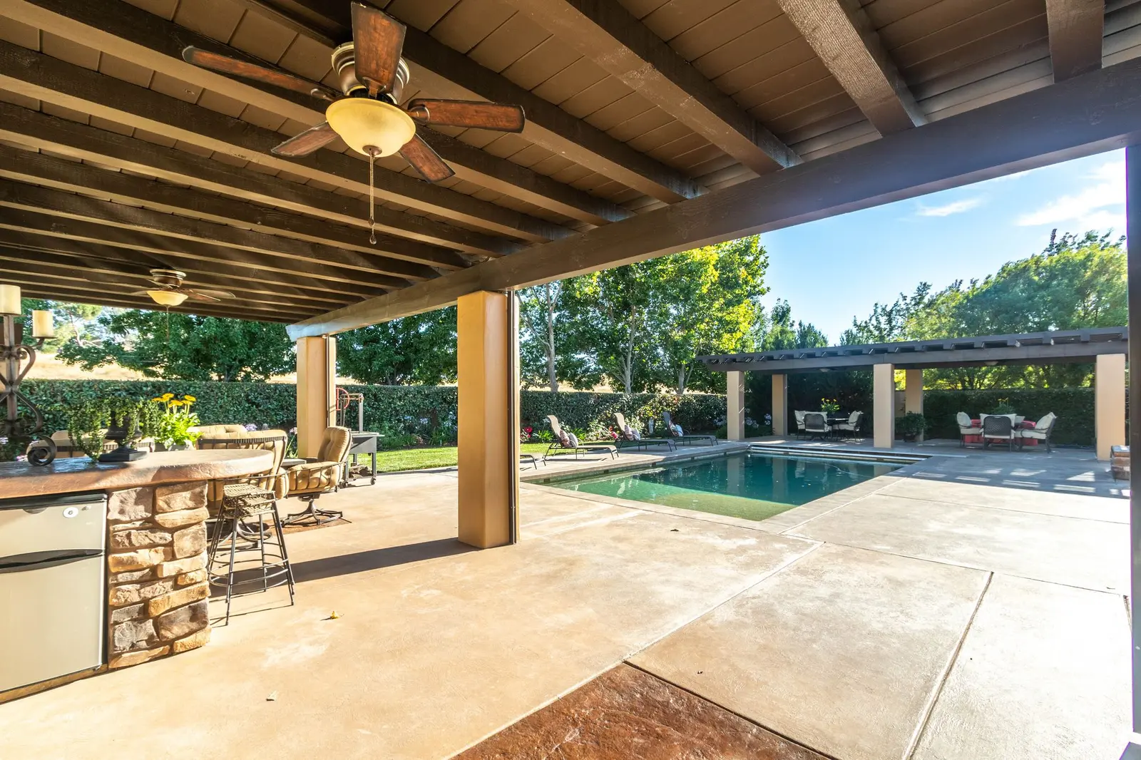 Covered outdoor kitchen and bar looking out to a pool