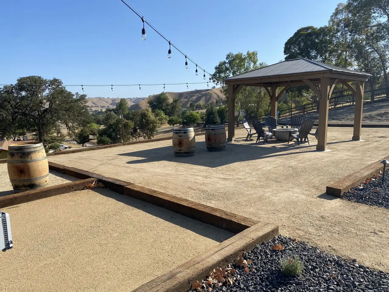 Decomposed granite bocce court beside a gazebo with string lights