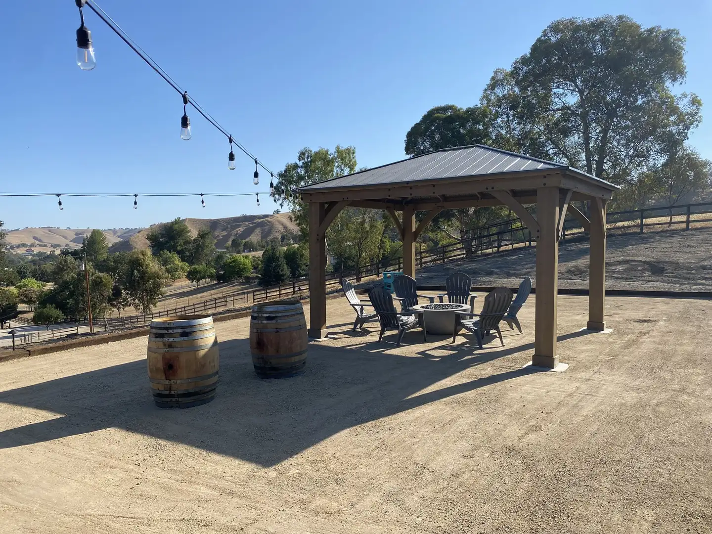 Gazebo with string lights over a decomposed granite patio with wine barrels