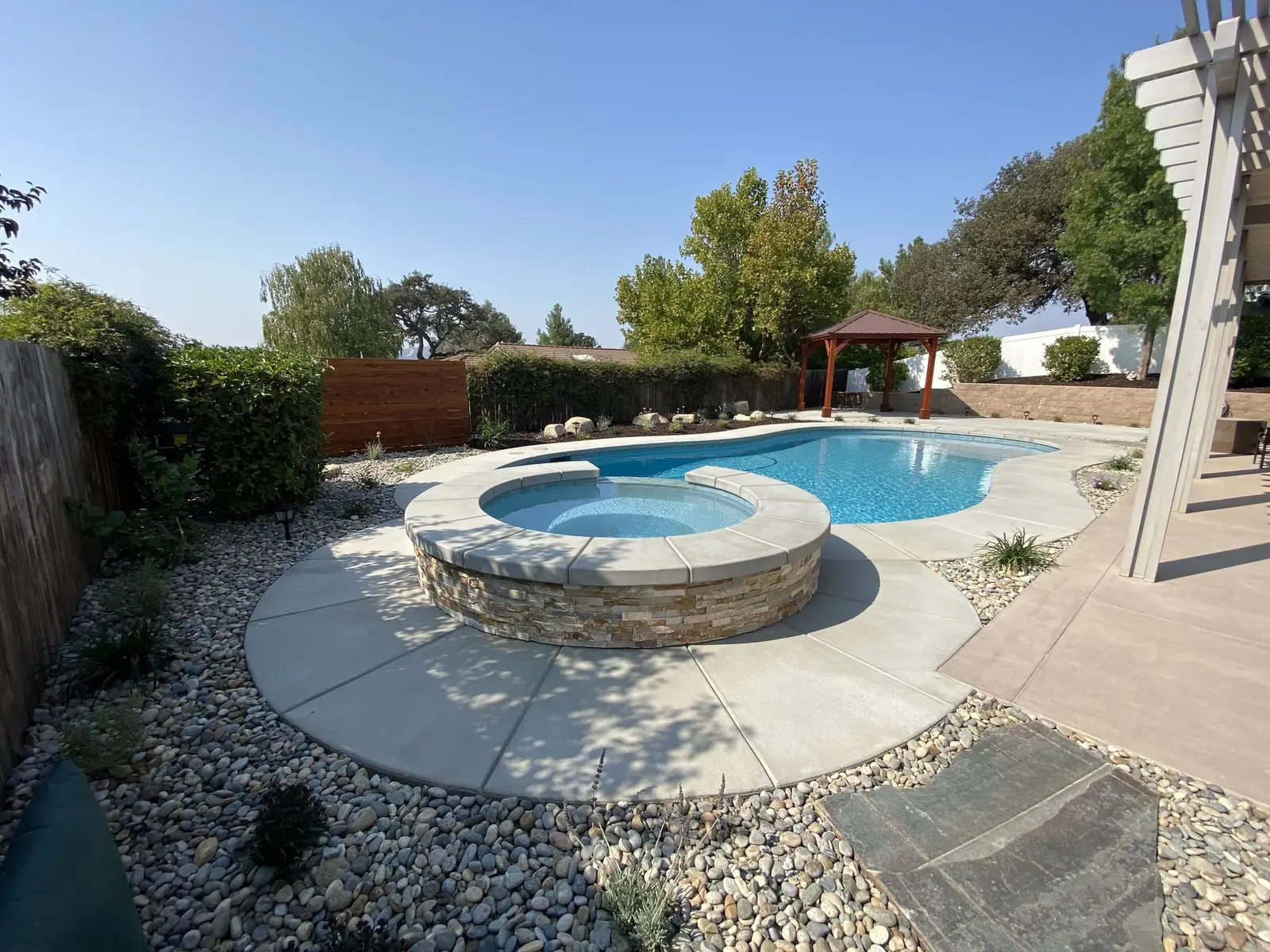 Pool with a raised stone spa and gravel planting beds