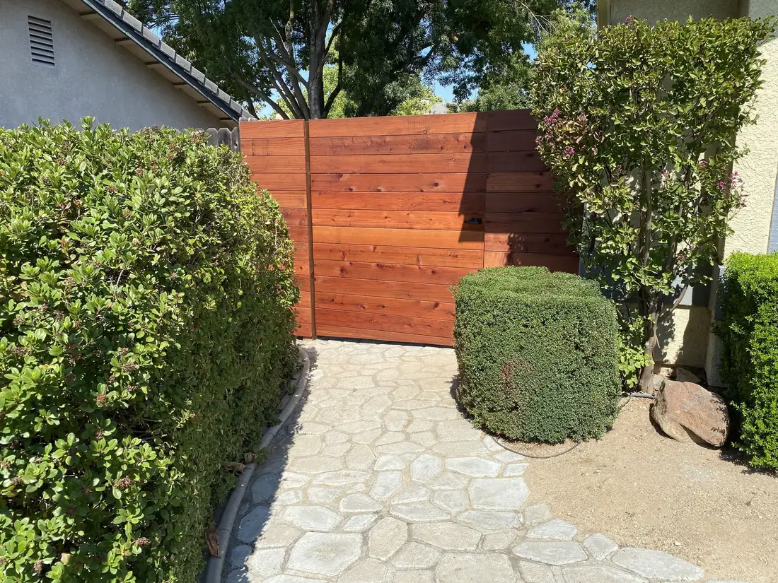 Redwood horizontal fence and gate beside stamped concrete