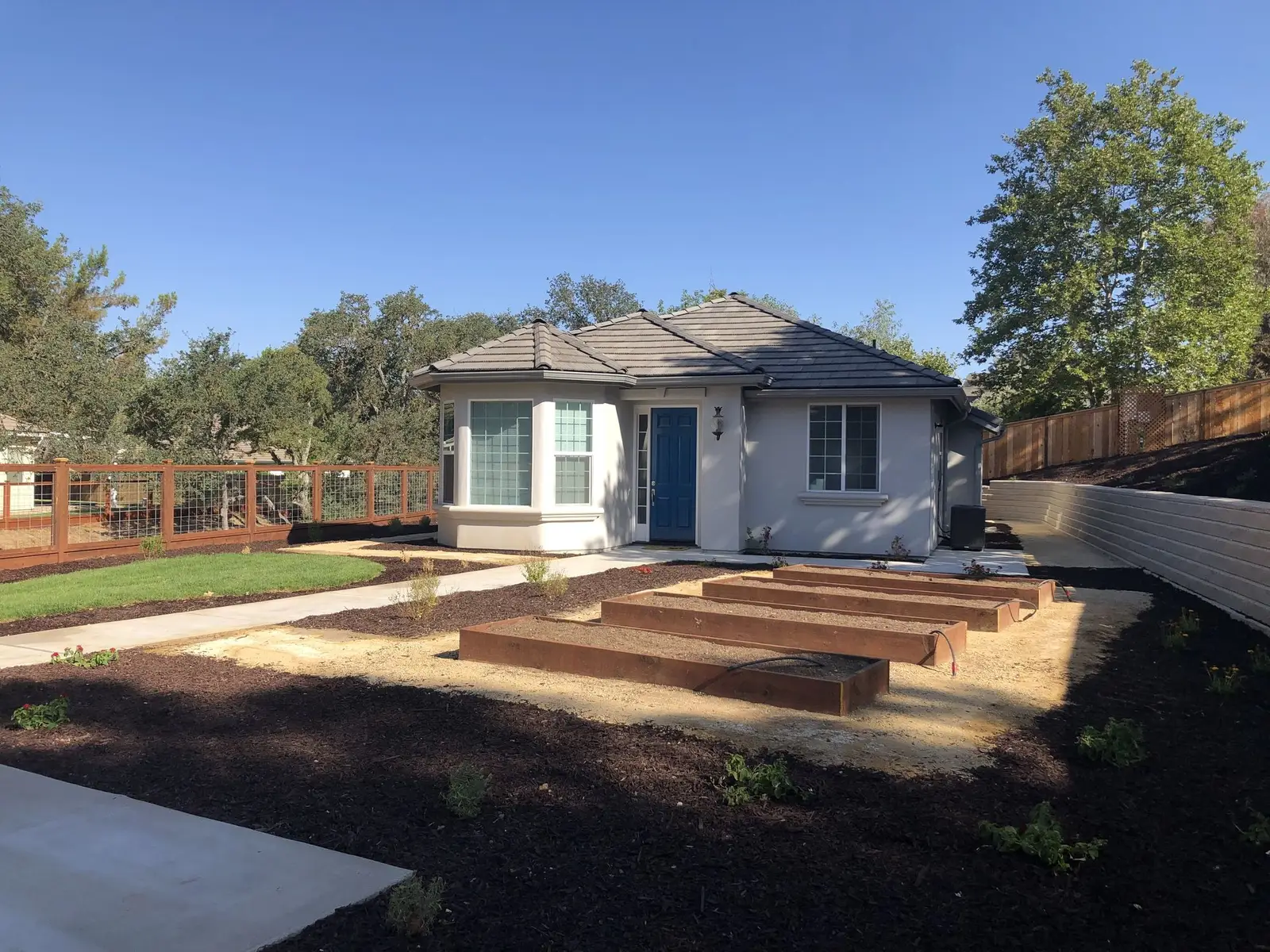 Redwood raised beds on a decomposed granite front yard beside a cottage