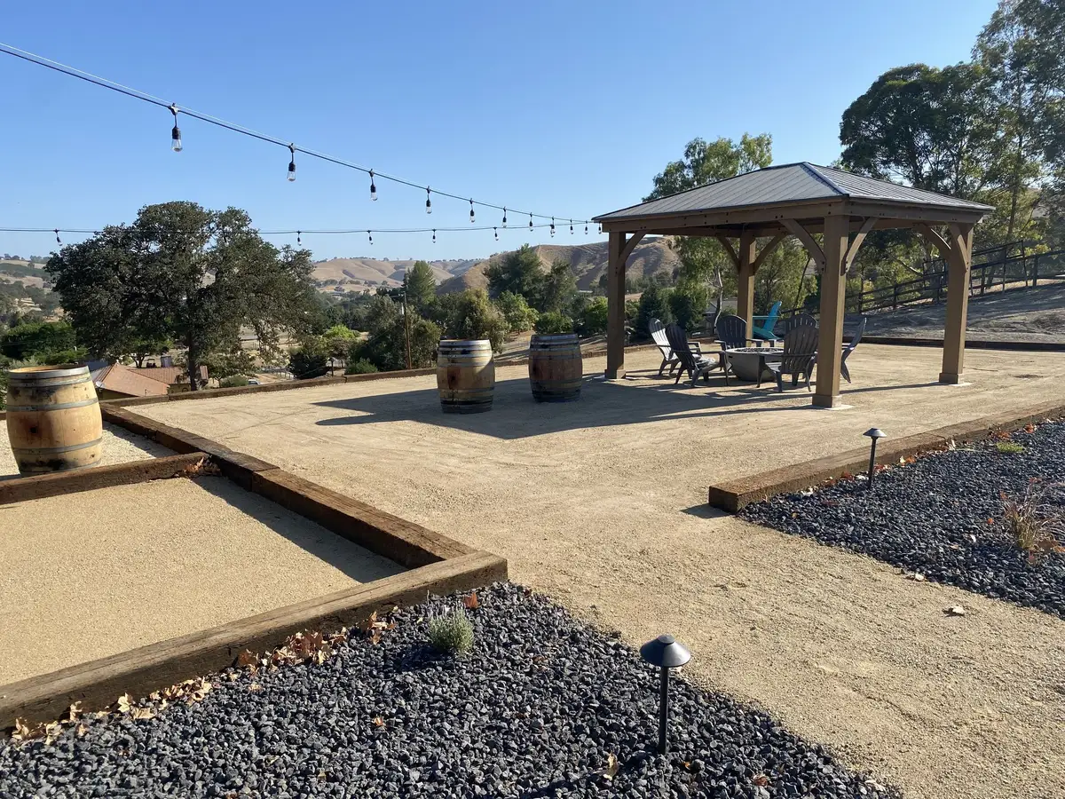 Decomposed granite court with timber edging and gravel beds under string lights