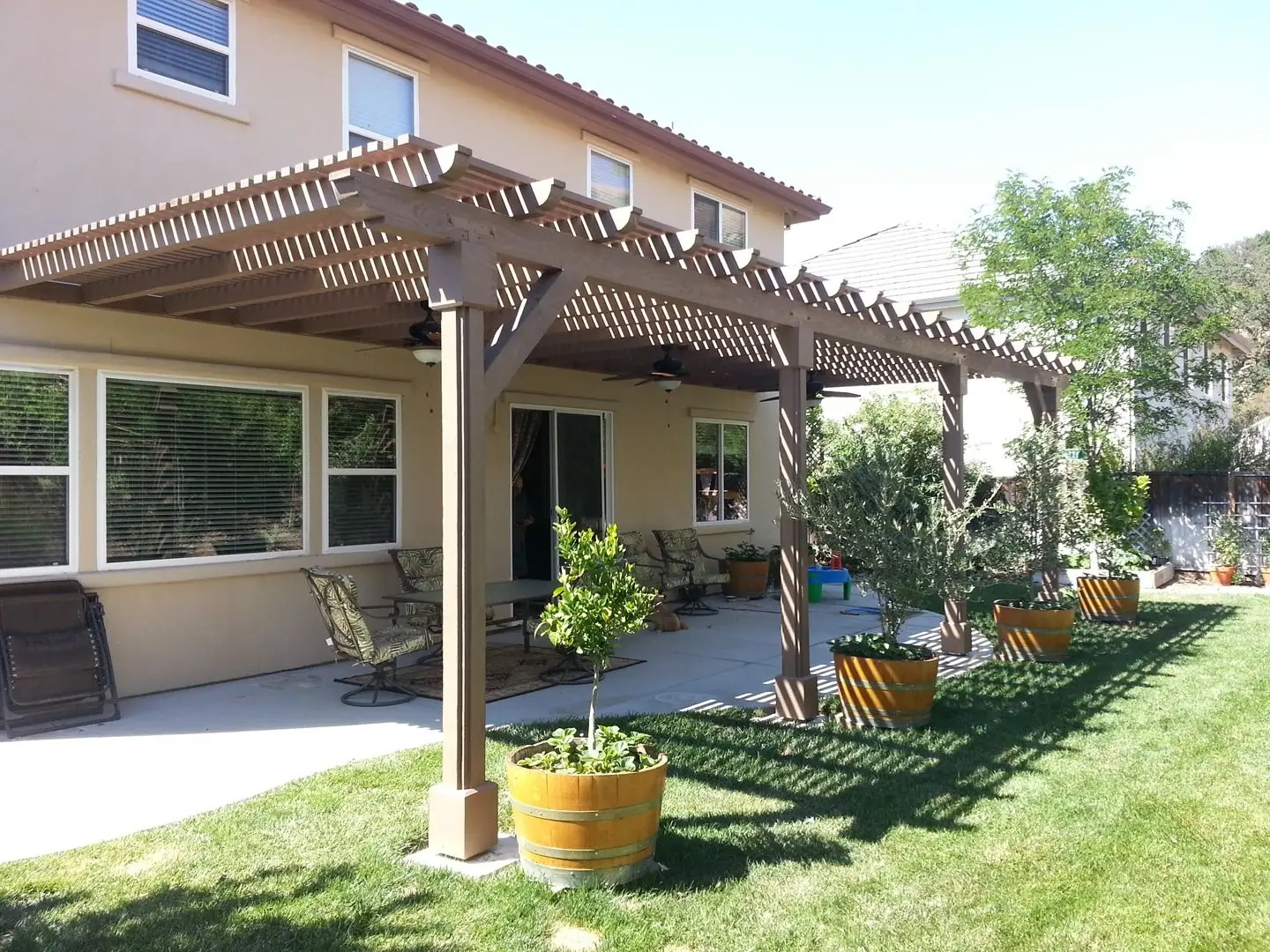Timber lattice patio cover attached to a home beside a lawn