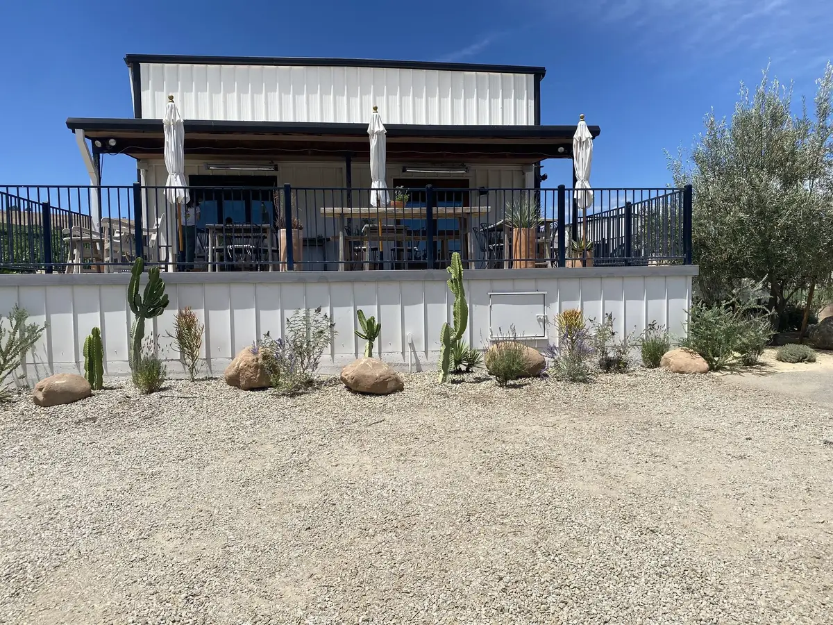 Gravel yard with boulders, cactus and agave below a raised building deck