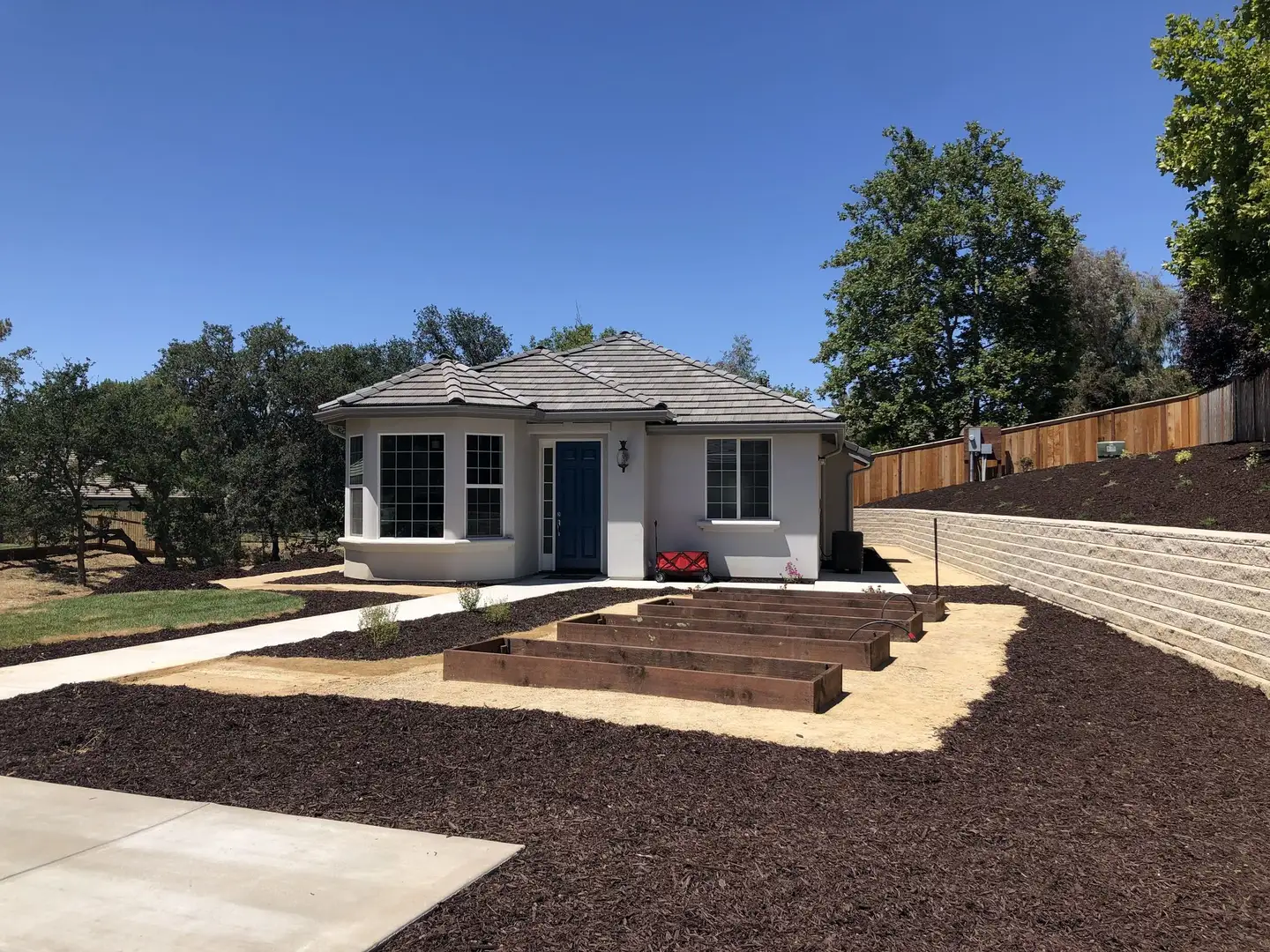 Redwood raised beds on a decomposed granite yard in front of a small cottage