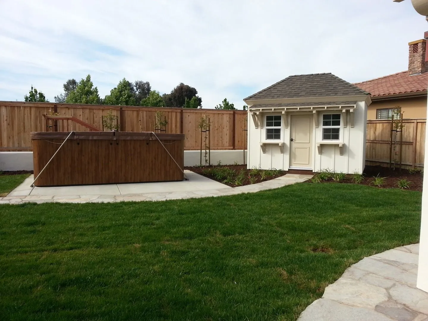 Backyard lawn with a garden shed and redwood raised beds along the fence