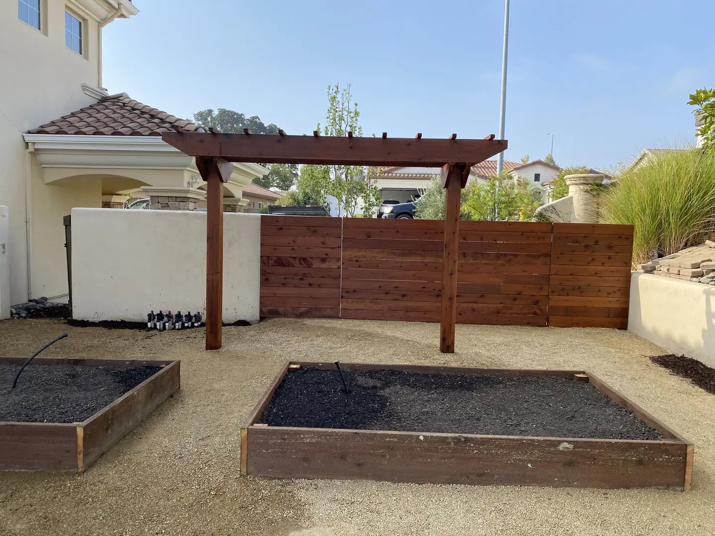 Raised garden beds with a pergola and privacy fence